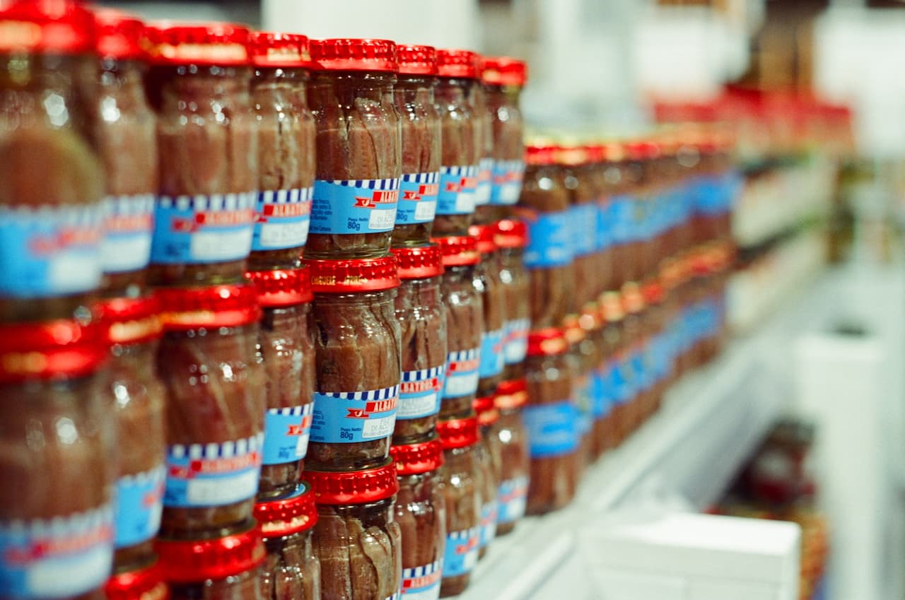 Stacked jars of anchovies on a market shelf