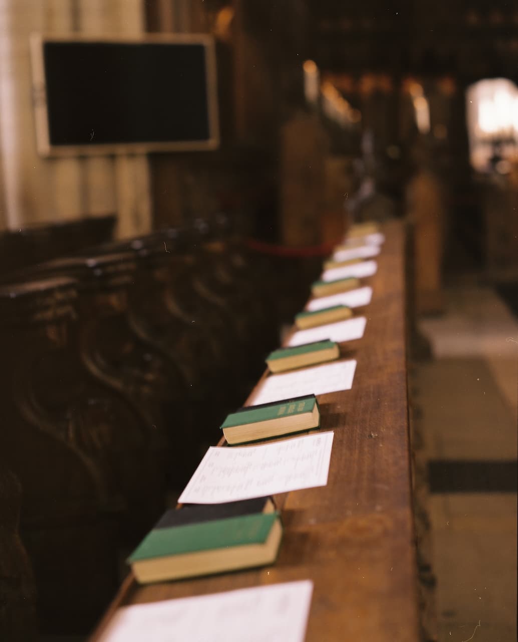 Hymn books and song sheets laid out along a church pew