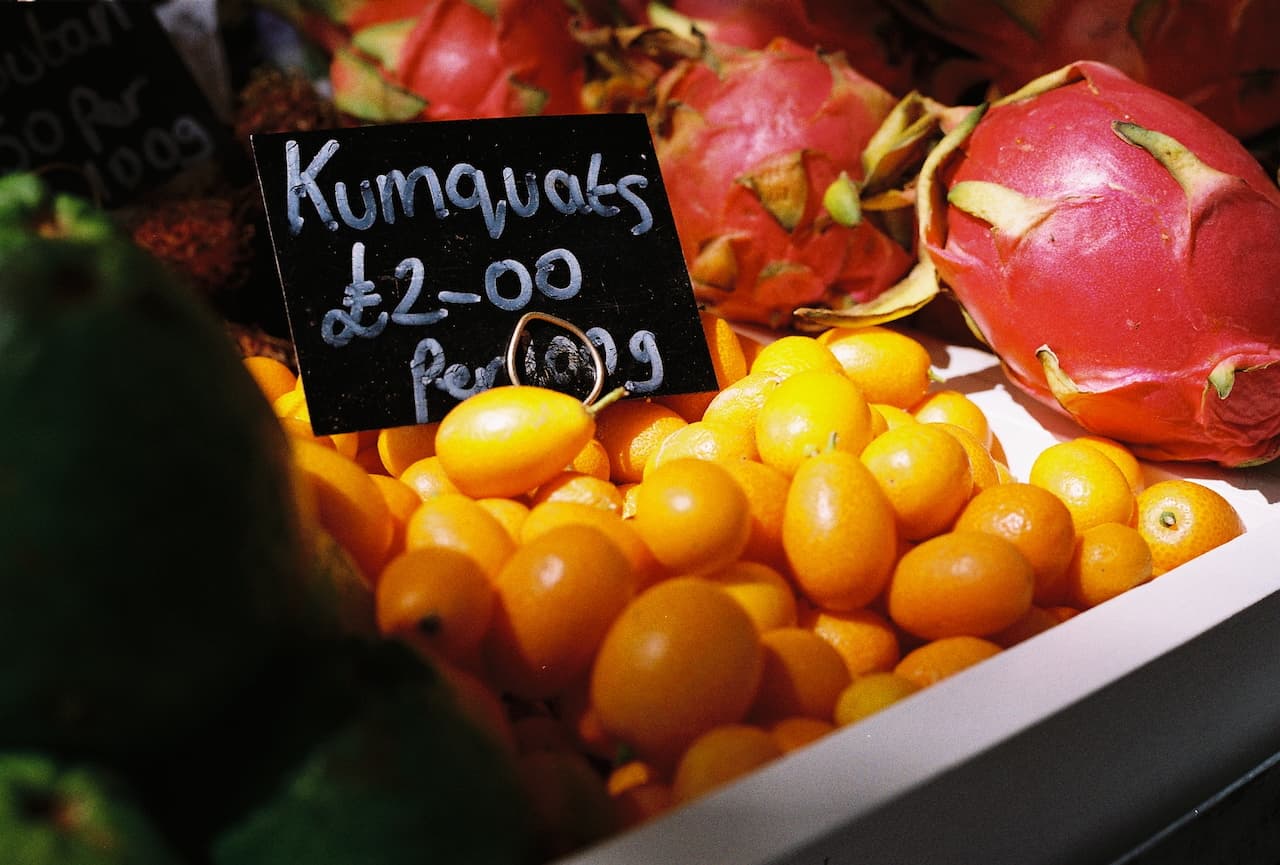 Pile of kumquats with handwritten price sign at a market